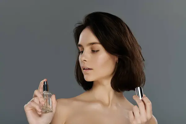 A woman holds a bottle of perfume, looking at it thoughtfully. — Stock Photo