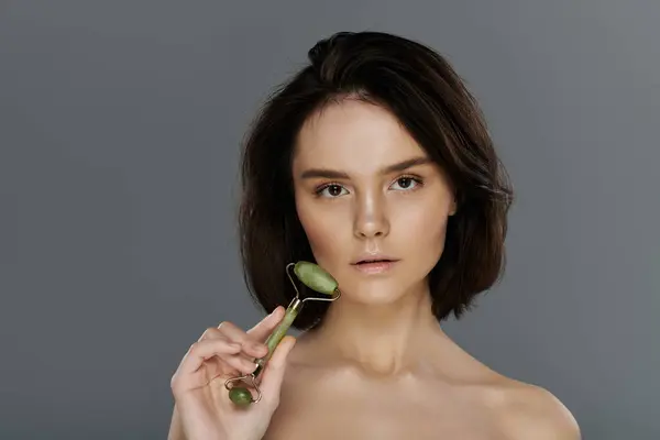 A woman uses a jade roller on her face in a close-up portrait. — Stock Photo