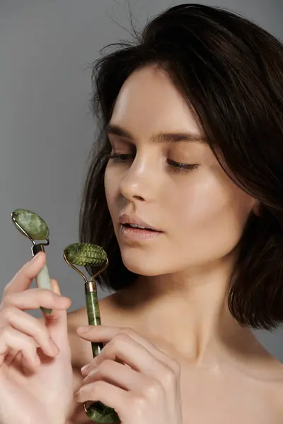 A woman holds two jade rollers in her hands. — Stock Photo