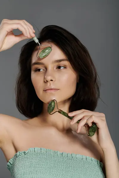 Eine Frau benutzt eine Jadewalze auf ihrem Gesicht als Teil einer Hautpflege-Routine. — Stockfoto