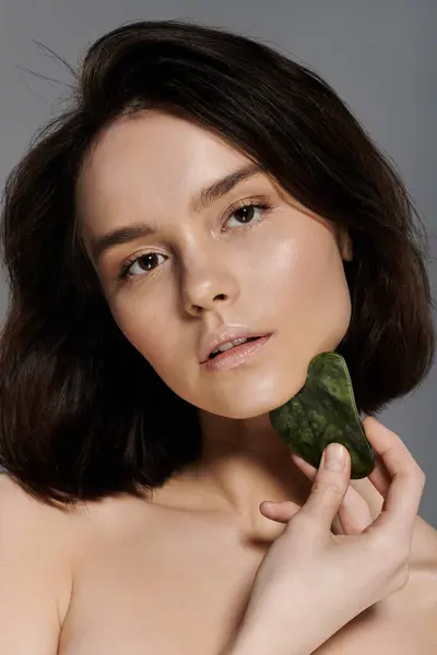 A woman uses a gua sha on her face, highlighting her natural beauty. — Stock Photo