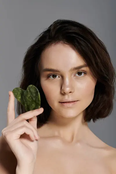 Portrait of a woman holding a green jade gua sha tool. — Stock Photo