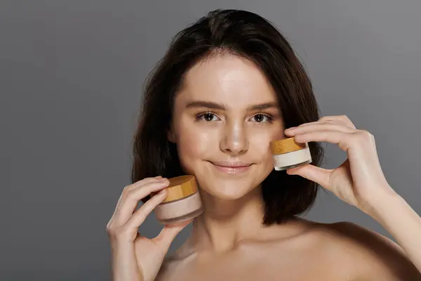 A woman smiles brightly while holding two jars of natural skincare products. — Stock Photo