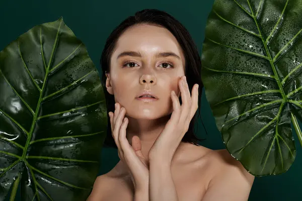 A woman poses in front of a vibrant green backdrop, touching her face with delicate hands. — Stock Photo