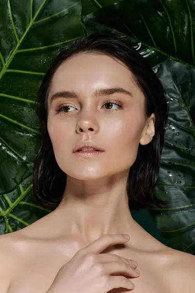 Una bella donna con i capelli bagnati posa su uno sfondo di foglie verdi vibranti. — Foto stock