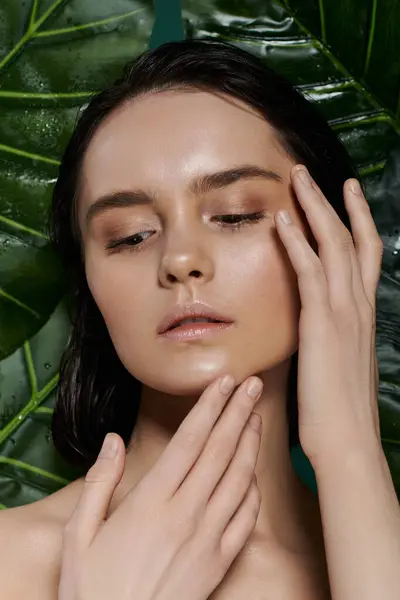 A woman with flawless skin poses against a vibrant backdrop of lush green foliage. — Stock Photo