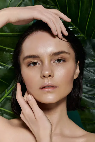 Une femme aux cheveux foncés pose parmi un feuillage vert vif. — Photo de stock
