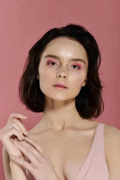 A portrait of a woman with pink eyeshadow posing against a vibrant pink background. — Stock Photo