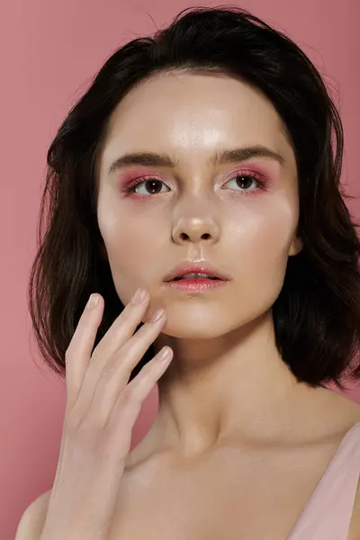A woman with pink eyeshadow poses against a vibrant pink background. — Stock Photo