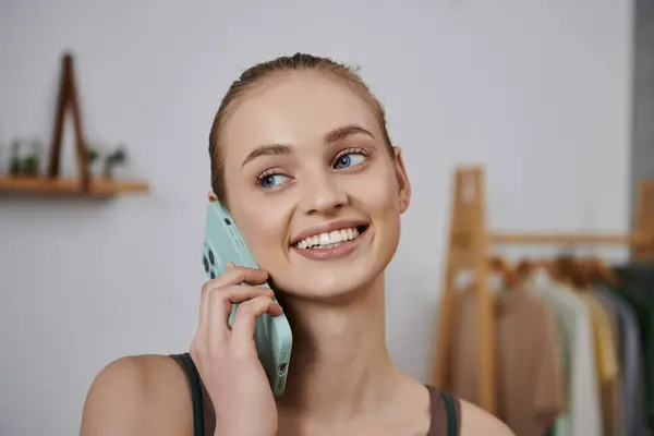 A young woman smiles while on a phone call at home. — Stock Photo