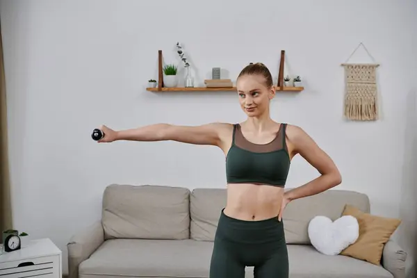 A young woman exercises with weights in her home. — Stock Photo