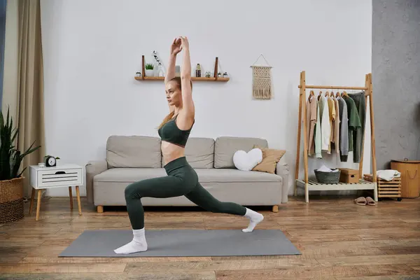 A young woman in athletic wear stretches on a yoga mat in her living room. — Stock Photo