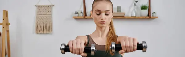A young woman lifts weights during a home workout. — Stock Photo