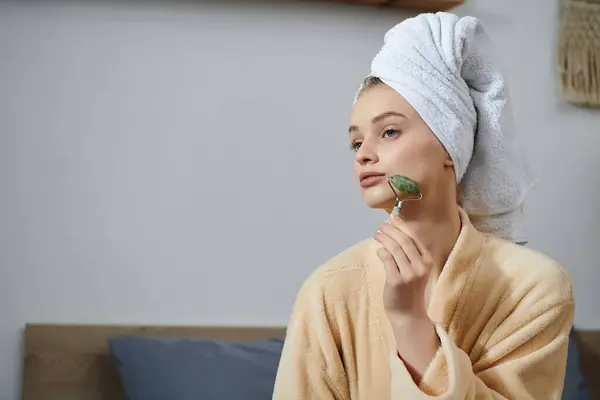 Eine junge Frau entspannt sich zu Hause mit einer Jadewalze im Gesicht. — Stockfoto