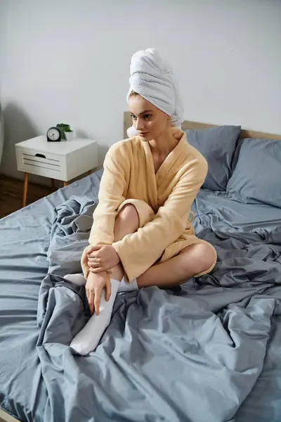 A young woman in a robe relaxes on a bed, enjoying a peaceful moment at home. — Stock Photo