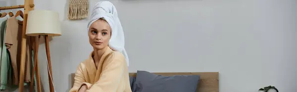 A young woman relaxes at home, wearing a towel on her head and a robe. — Stock Photo