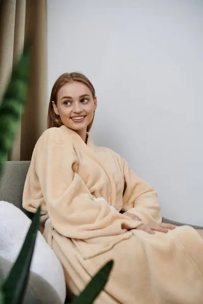 Une jeune femme se détend dans une robe moelleuse à la maison, profitant d'un moment de calme. — Photo de stock