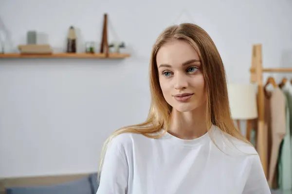 A young woman pauses in her home, gazing thoughtfully off-camera. — Stock Photo