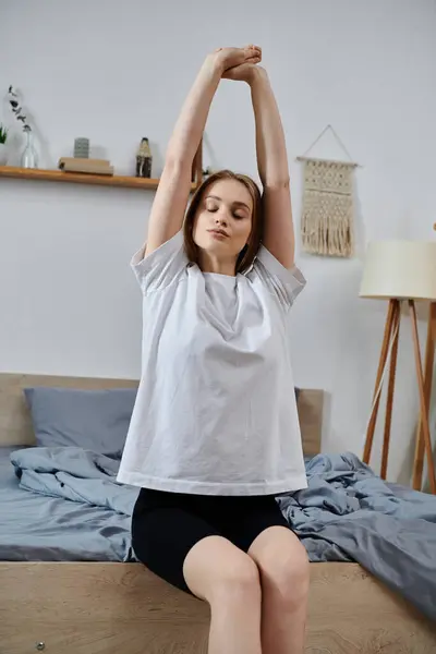 A young woman stretches on her bed in the morning. — Stock Photo
