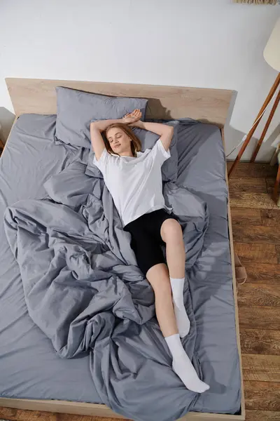 Eine junge Frau schläft friedlich in ihrem Bett und genießt den Komfort ihres Hauses. — Stockfoto