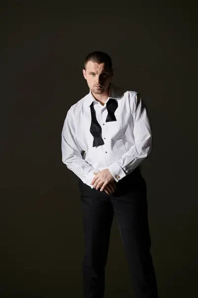 Man in white shirt, black bow tie, focused gaze against dark background. — Stock Photo