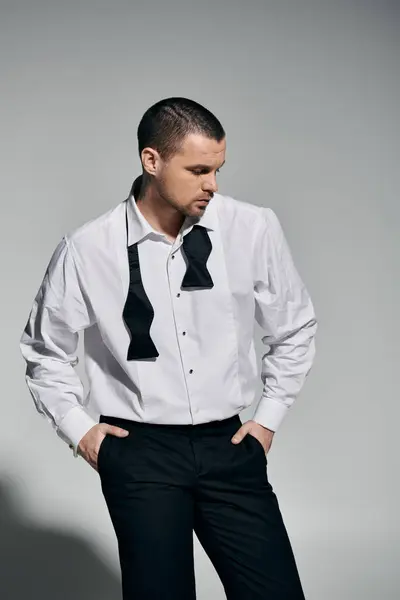 A man in a white shirt and black bow tie stands with his hands in his pockets. — Stock Photo