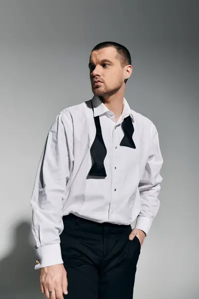 A stylish man in a white shirt and black bow tie poses against a grey background. — Stock Photo