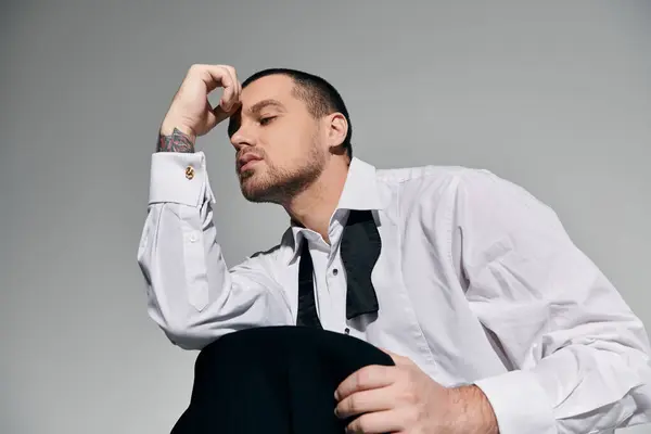 A stylishly dressed man ponders in a quiet studio. — Stock Photo