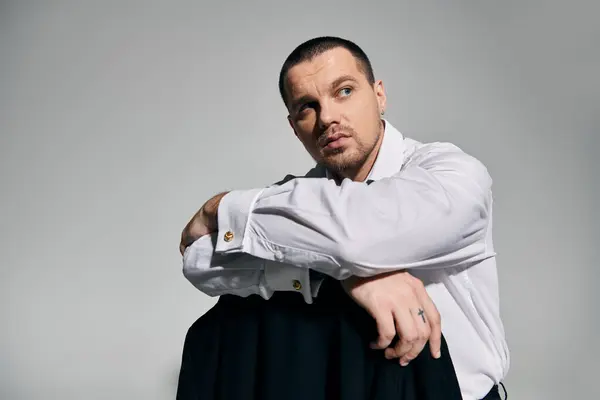 A man in a crisp white shirt, sits thoughtfully, his gaze directed off-camera. — Stock Photo