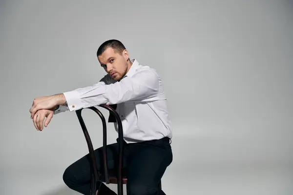 Чоловік у хрусткій білій сорочці і чорні штани спирається назад на дерев'яний стілець. — Stock Photo