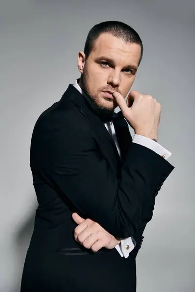 A man in a tuxedo thoughtfully ponders, his gaze intense and his hand resting on his chin. — Stock Photo