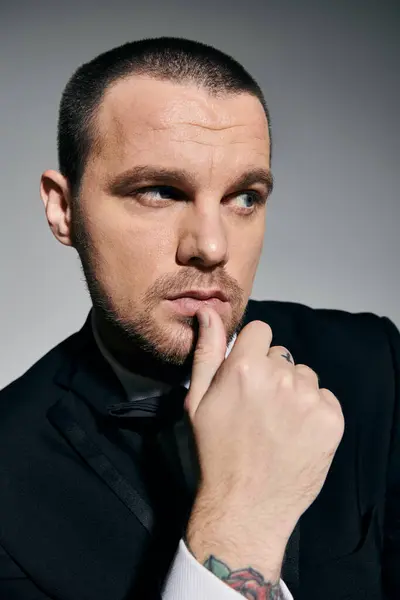 A stylish man in a black suit and bow tie, with a thoughtful expression. — Stock Photo
