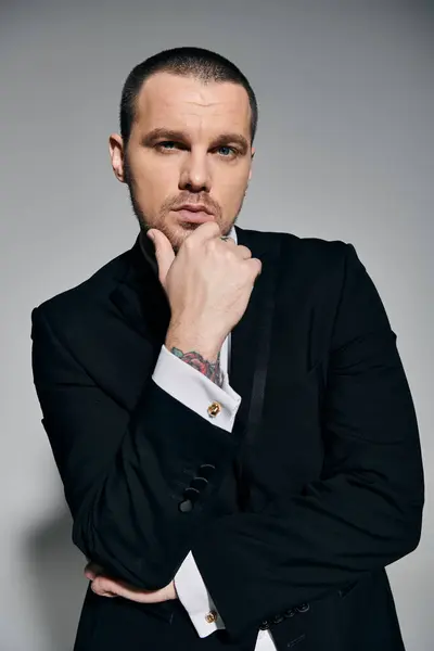 A man in a sharp black suit with a white shirt stares thoughtfully into the camera. — Stock Photo