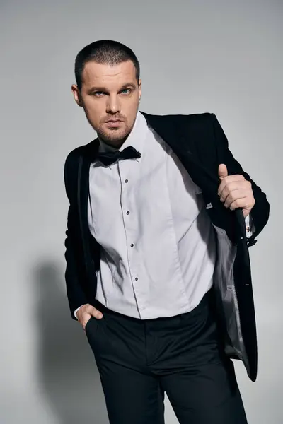 A man in a tuxedo stands confidently, adjusting his jacket with a sophisticated air. — Stock Photo