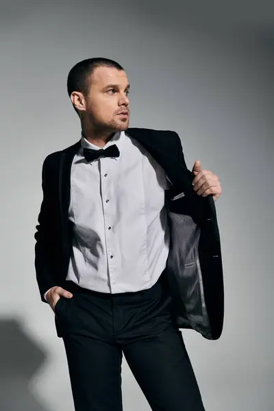 Man in tuxedo stands confidently, hand in pocket, gaze fixed off-camera. — Stock Photo