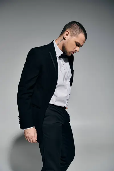Uomo in smoking sullo sfondo grigio, trasudando fiducia tranquilla. — Foto stock