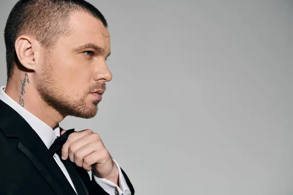 A man in a suit adjusts his bow tie, exuding sophistication and confidence. — Stock Photo