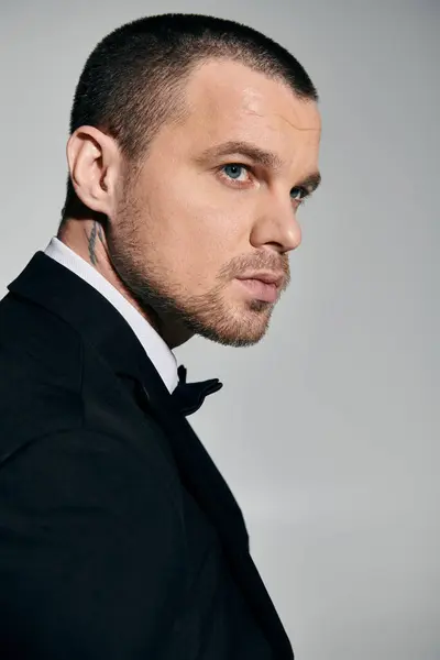 A man in a black tuxedo looks to the side, showcasing his sophisticated style. — Stock Photo