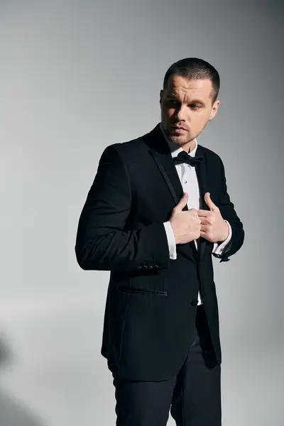 A man in a tuxedo adjusts his bowtie, looking sharp and confident. — Stock Photo