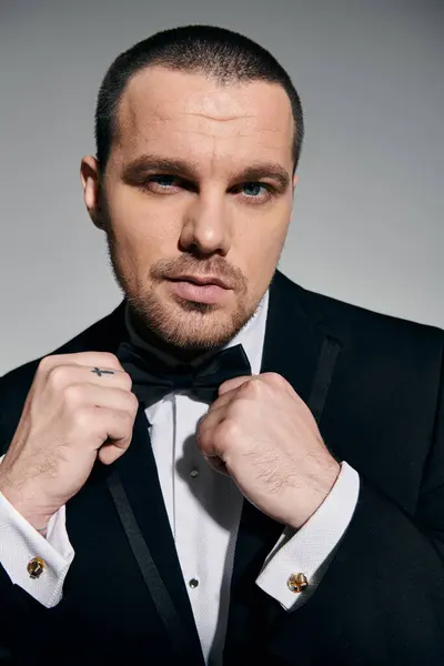 A man in a tuxedo adjusts his bowtie, a look of quiet confidence in his eyes. — Stock Photo