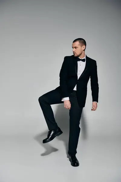 Uomo elegante in smoking con fiducia sguardi sopra la spalla, alzando la gamba. — Foto stock