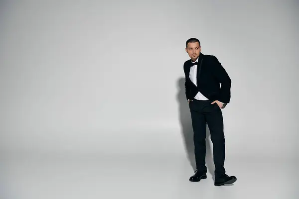 Um homem de smoking fica confiante na frente de um fundo branco liso. — Fotografia de Stock