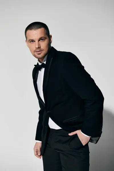 Man in black velvet suit, white shirt, black bow tie, stands confidently against neutral backdrop. — Stock Photo