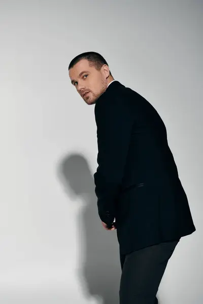A stylish man in a black suit looks over his shoulder. — Stock Photo