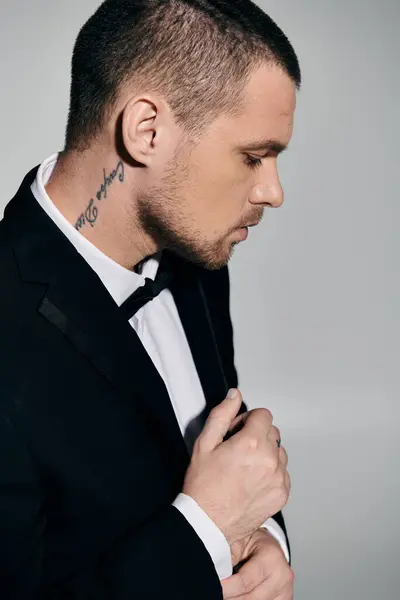 A man in a tuxedo adjusts his cufflinks while looking down. — Stock Photo