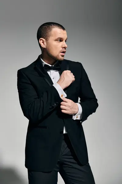 A man in a tuxedo adjusts his cufflinks while looking off to the side. — Stock Photo