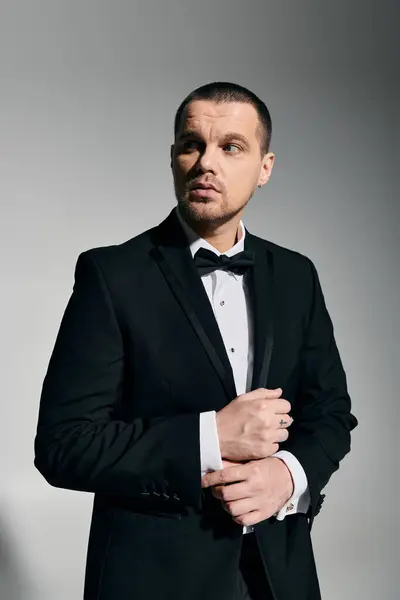 A man in a tuxedo, adjusting his cufflinks with a look of confidence. — Stock Photo