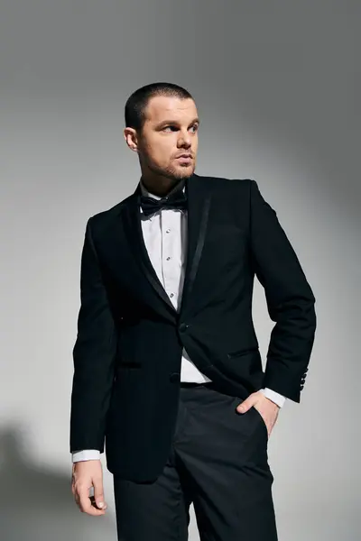 A man in a tuxedo stands with one hand in his pocket, looking to the side. — Stock Photo