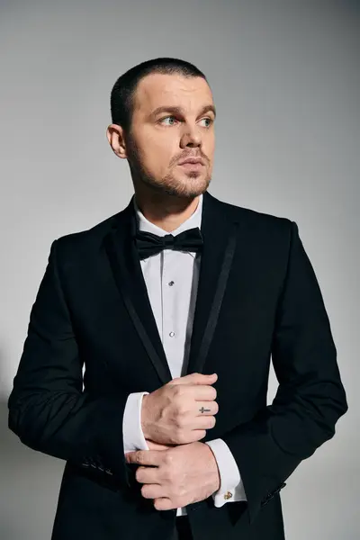 A man in a black suit and bow tie stands with a thoughtful expression. — Stock Photo