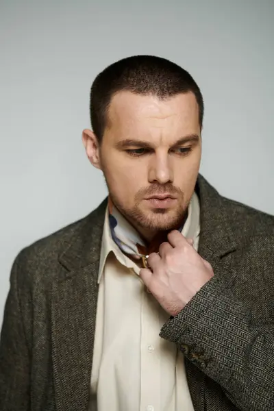 A man in a stylish tweed jacket adjusts his collar with a thoughtful expression. — Stock Photo